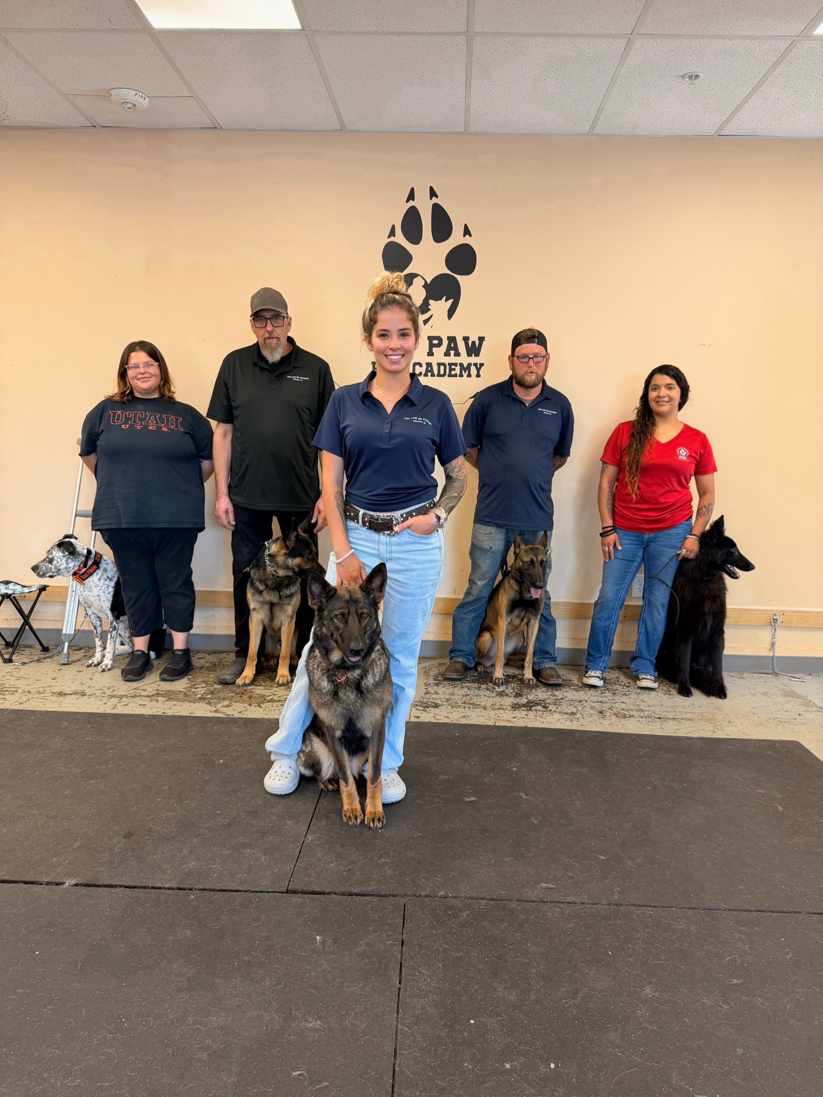 Top Paw K9 Academy team members standing with dogs inside the training facility